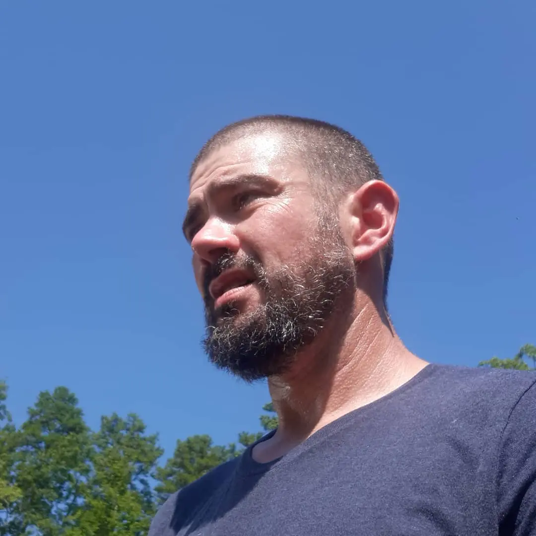 Bearded man photographed against a clear blue sky